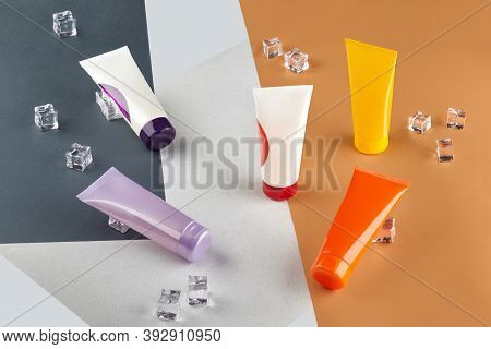 Five Cosmetic Tubes With No Logo Or Label And Ice Cubes On Colorful Surface Or Background. Advertisi