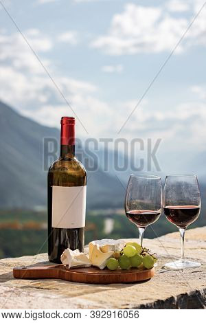 Glass Of Red Wine And Mountains On Background. Swiss Cheese And Wine