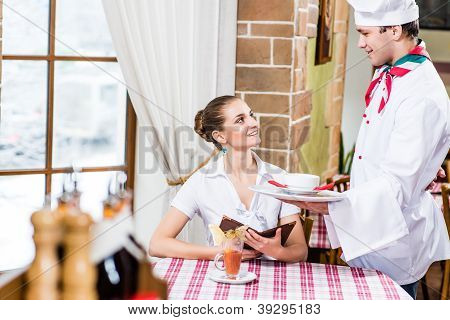 Lo chef porta una donna abbastanza piatto in un ristorante