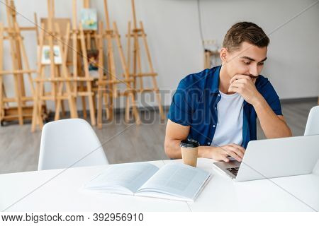 Young designer entrepreneur working on laptop while sittng in his studio work space