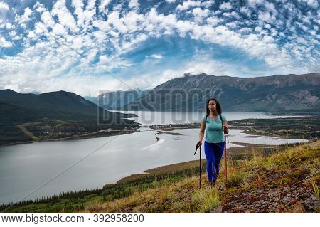 Adventurous Girl Hiking Up The Nares Mountain During A Cloudy And Sunny Day. Taken Near Whitehorse, 