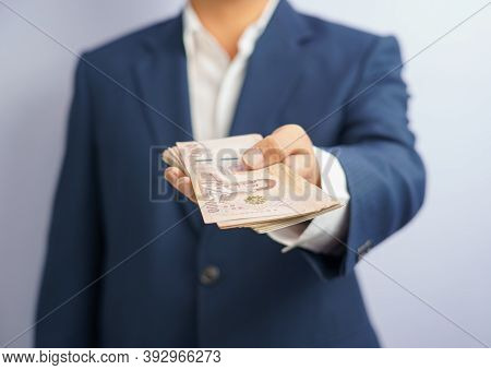 Money In Thailand Hold On Hand Business Man Grabbing Wearing A Blue Suit, Filed And Put And Give To 