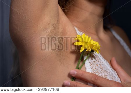 Young Girl With Hairy Armpits, Holding A Flower In Her Hand. Caring For The Vegetation Under The Arm