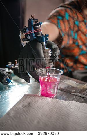 Hand Of Tattooer And A Tattoo Machine.