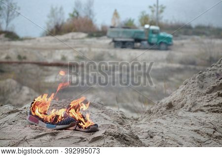 Burning Sports Sneakers Or Gym Shoes On Fire Stand On Sandy Beach Coast. Athlete Burned Out. Physica