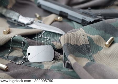 Army Dog Tag Token With 9mm Bullets And Pistol Lie On Folded Camouflage Green Fabric