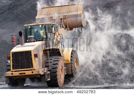 Front loader dumping mineral material on heap