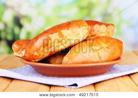 Empanadillas al horno frescos, en mesa de madera, sobre fondo brillante