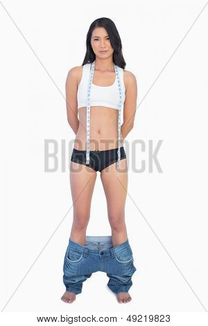 Self selvsikker kvinde iført jeans falder ned, fordi shes mistede vægt på hvid baggrund