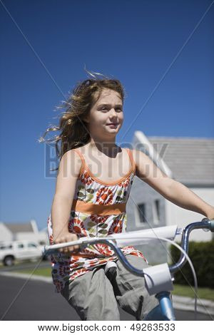 Låg vinkel syn på en ung flicka ridning cykel på gatan