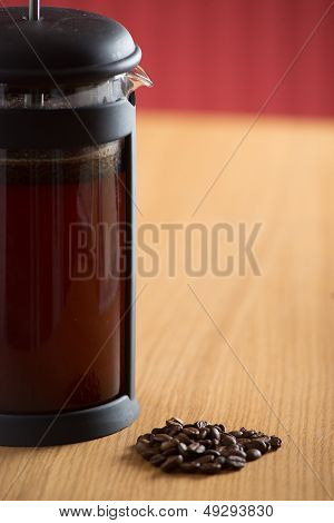 Closeup di caffettiera con chicchi di caffè di fronte
