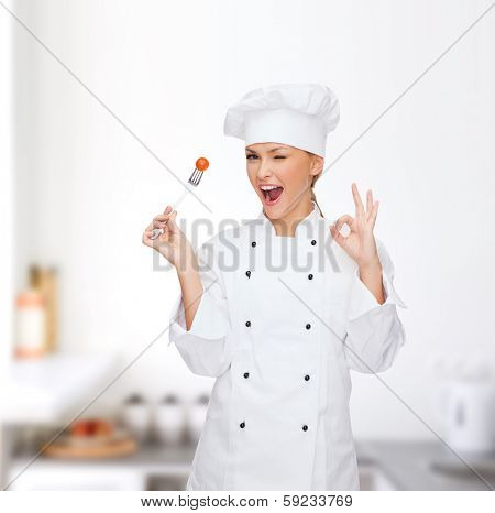 cooking and food concept - smiling female chef, cook or baker with fork and tomato showing ok sign