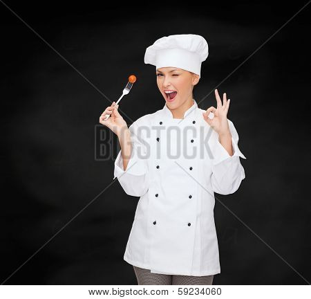 cooking and food concept - smiling female chef, cook or baker with fork and tomato showing ok sign