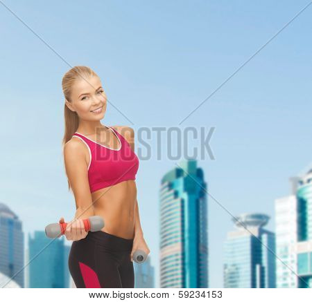 fitness and dite concept - young sporty woman with light dumbbells