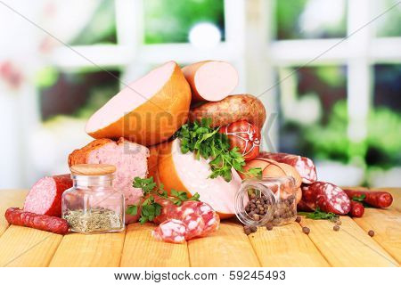 Lot of different sausages on wooden table on window background