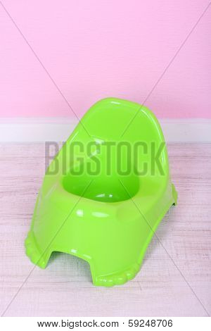 Green potty on floor, on wall background