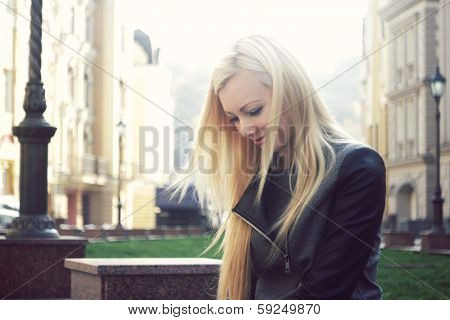 Happy young beautiful blonde woman smiling on the street in a jacket