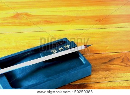 Inkstand, Ink-stick And Brushes On Wooden Table