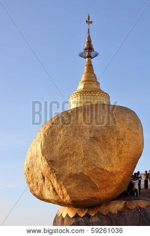 KYAIKTIYO, MYANMAR - DECEMBER 15, 2013: Kyaiktiyo pagoda (Golden Rock) with pilgrims and praying people. According to tradition, the faithful attaching petals of gold leaf to the Gold Stone
