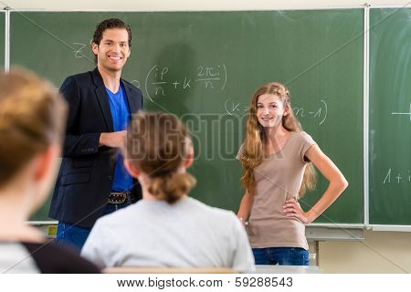 School class Teacher or educator testing in a lessons students in front of the class at the blackboard or board or chalkboard in math