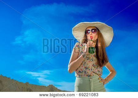 Young Woman Drinking From The Bottle On The Sky Background On The Summer