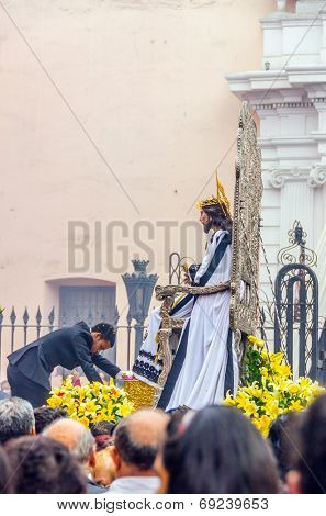 LIMA, PERU, MAY 25, 2014 - Man decorates Statue of Christ with flowers during religious procession 
