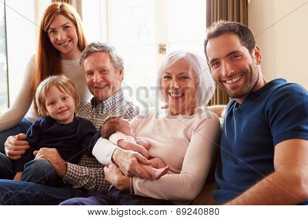Multi Generation Family Sitting On Sofa With Newborn Baby