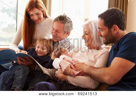 Multi Generation Family Sitting On Sofa With Newborn Baby