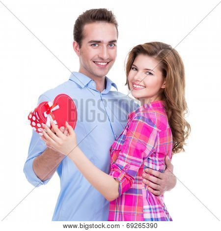 Happy young couple with a gift in a studio isolated on a white background.