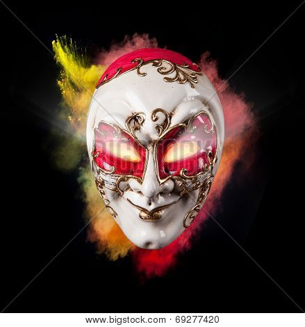 Isolated Venice mask with freeze motion of colored powder on black background