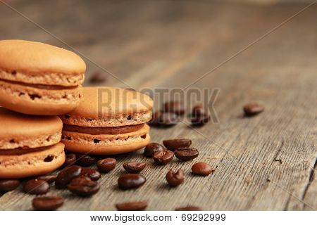 Three coffee macarons on a table with coffee beans
