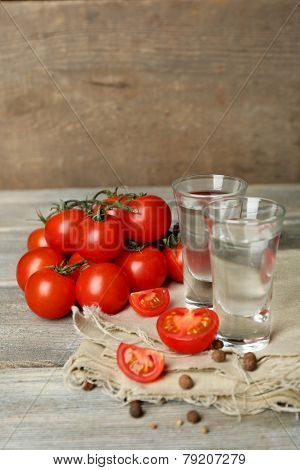 Glasses of ouzo and tomatoes on wooden table