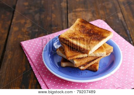 Toast bread on blue plate with pink napkin, on wooden table background