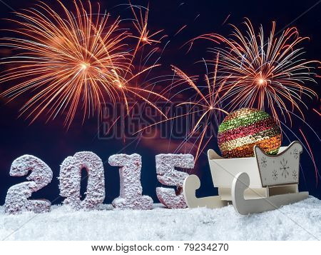 Frosted 2015 New Year digits and big glistering ball in wooden sleigh over dark blue sky with fireworks