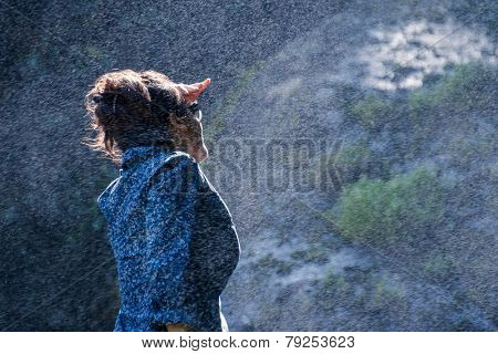 Young Nepalese woman standing in the water spray from a waterfall