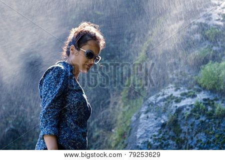 Young Nepalese woman standing in the water spray from a waterfall