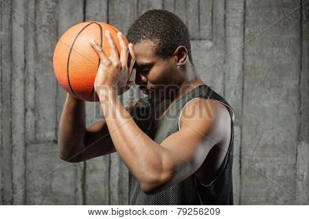 Afro-american basketball player pressing ball to his forehead