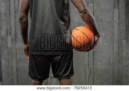 Afro-american basketball player holding the ball at his side