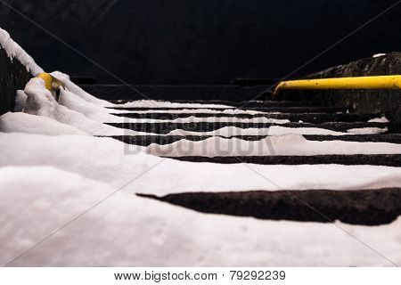 Snow covered stairs to dark water