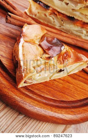 sweet food : apple pie cuts served on wooden plate over table with cinnamon sticks