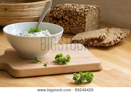 Curd Cheese Dip With Herbs In A Bowl And Rustic Bread In The Background
