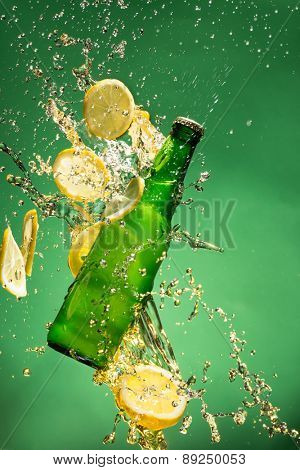 Green beer bottle with splashing liquid, freeze motion.