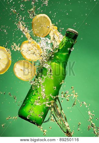 Green beer bottle with splashing liquid, freeze motion.