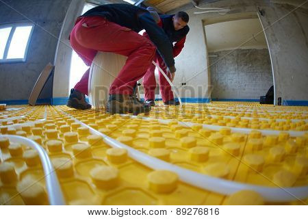 grouo of workera installing underfloor heating and colling in modern home