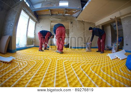 grouo of workera installing underfloor heating and colling in modern home