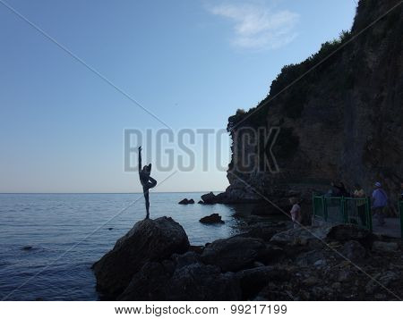 Girl on the stoun near sea in sunny summer day