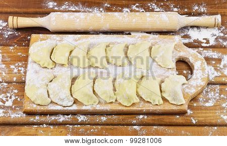 Vareniki with potatoes on a cutting board before cooking. Dumplings on a cutting board.