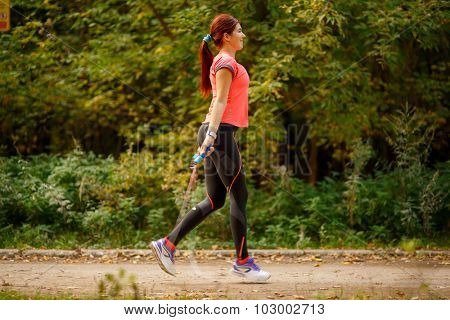 athletic young woman skipping with jump rope in park on summer day
