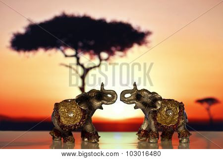 Two miniature elephant at sunset