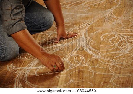 Skilled craftsman sketches carving design on wood before start carving work